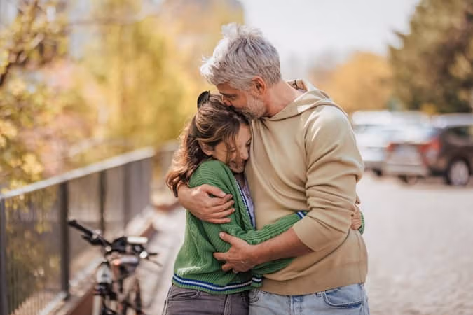 Teenage daughter hugging her father outside in town when spending time together
