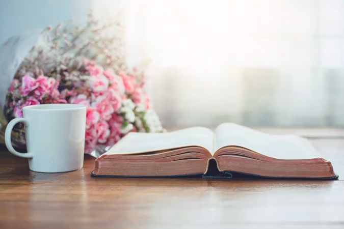 open Bible on desk with flowers.